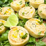 Close view of Mexican Street Corn Pinwheels (Roll Ups) laid out on a bed of cilantro.
