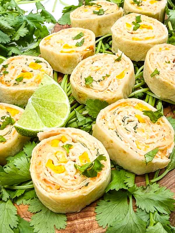 Close view of Mexican Street Corn Pinwheels (Roll Ups) laid out on a bed of cilantro.
