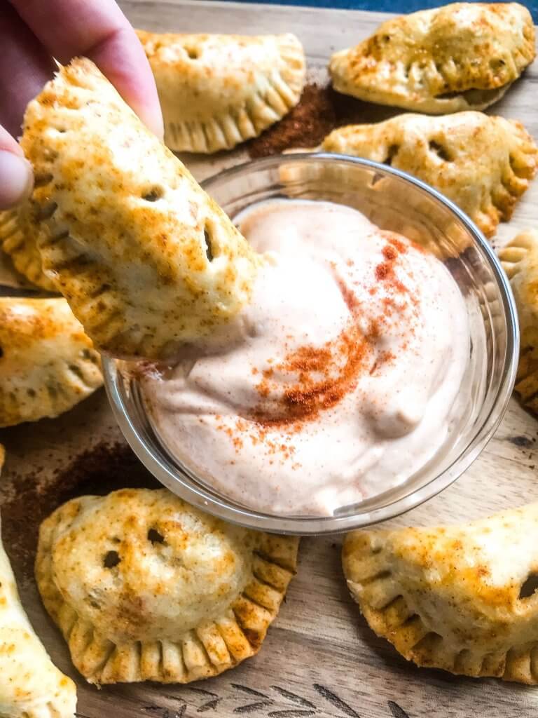Patatas Bravas Empanadas are inspired by a Spanish tapas recipe. Roasted seasoned potatoes are stuffed in dough and served with a creamy paprika sauce. A great vegetarian appetizer recipe for party and entertaining food. #papasbravas #patatasbravas #spanishfood #appetizerrecipe