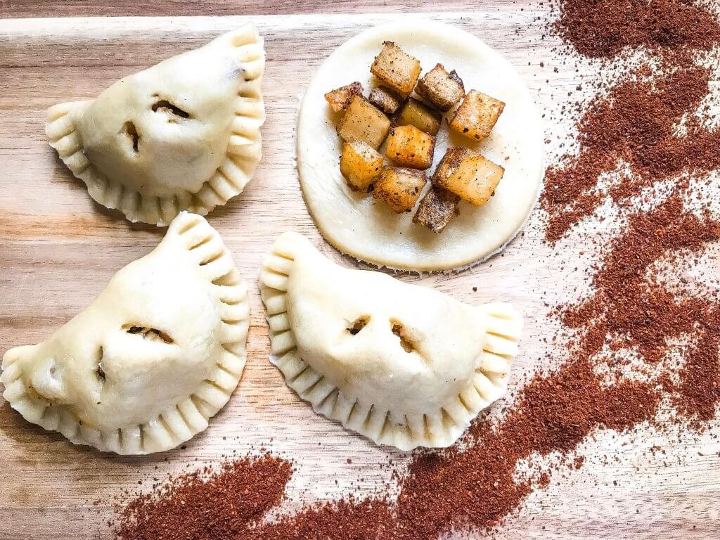 Patatas Bravas Empanadas are inspired by a Spanish tapas recipe. Roasted seasoned potatoes are stuffed in dough and served with a creamy paprika sauce. A great vegetarian appetizer recipe for party and entertaining food. #papasbravas #patatasbravas #spanishfood #appetizerrecipe