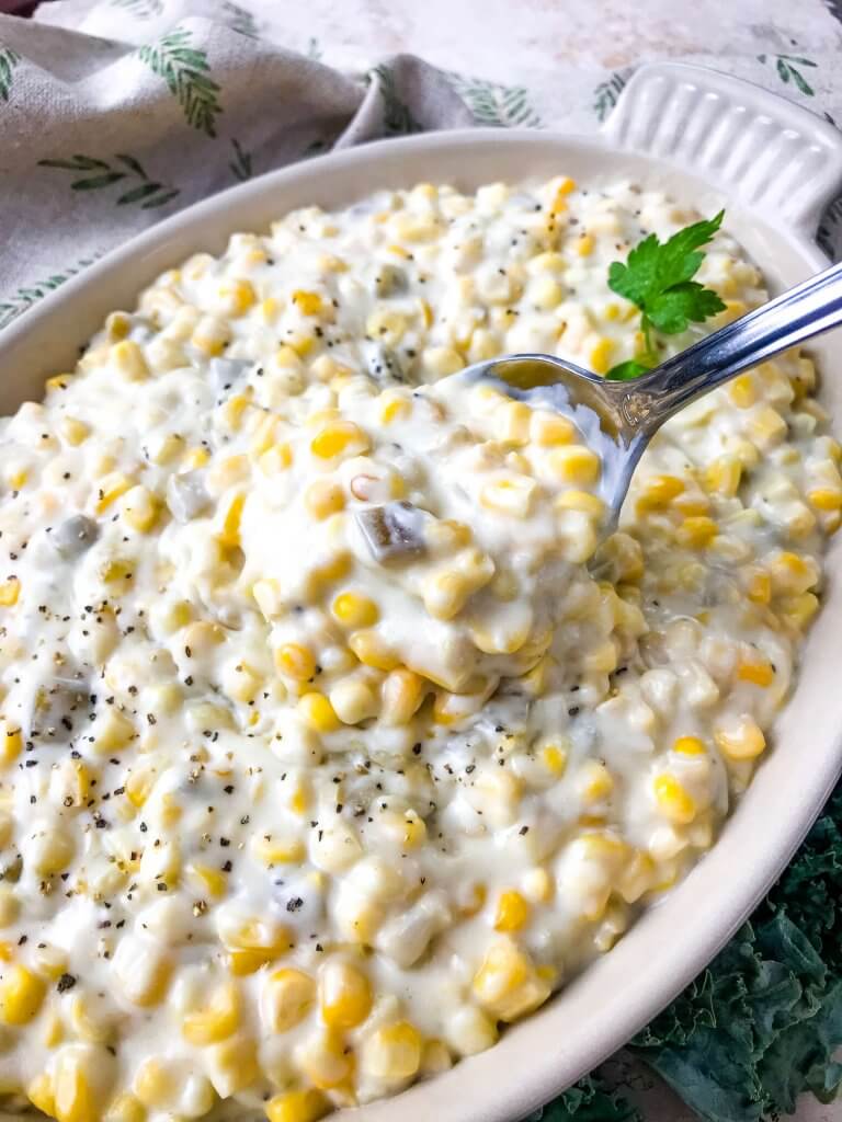 A spoon scooping Hatch Green Chile Creamed Corn in a dish