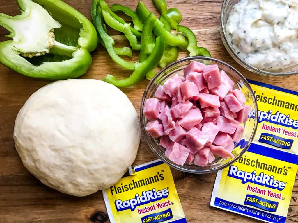 This Denver Omelet Pizza is ready in just 30 minutes using Fleischmann’s® RapidRise® Yeast, topped with a white sauce, ham, green bell peppers, and eggs. #HomemadePizzaCrust #homemadepizza