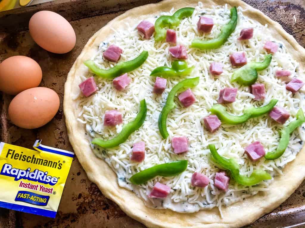 This Denver Omelet Pizza is ready in just 30 minutes using Fleischmann’s® RapidRise® Yeast, topped with a white sauce, ham, green bell peppers, and eggs. #HomemadePizzaCrust #homemadepizza