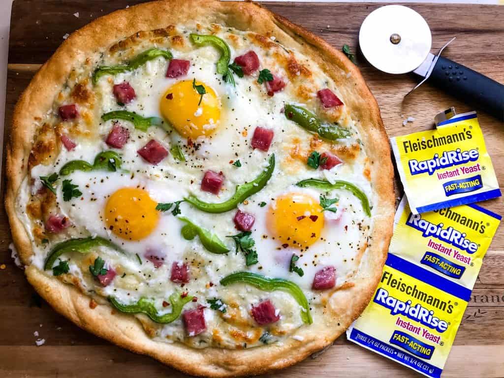 This Denver Omelet Pizza is ready in just 30 minutes using Fleischmann’s® RapidRise® Yeast, topped with a white sauce, ham, green bell peppers, and eggs. #HomemadePizzaCrust #homemadepizza