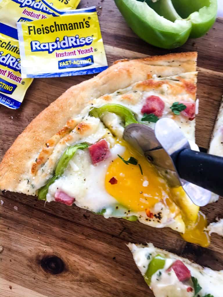 This Denver Omelet Pizza is ready in just 30 minutes using Fleischmann’s® RapidRise® Yeast, topped with a white sauce, ham, green bell peppers, and eggs. #HomemadePizzaCrust #homemadepizza