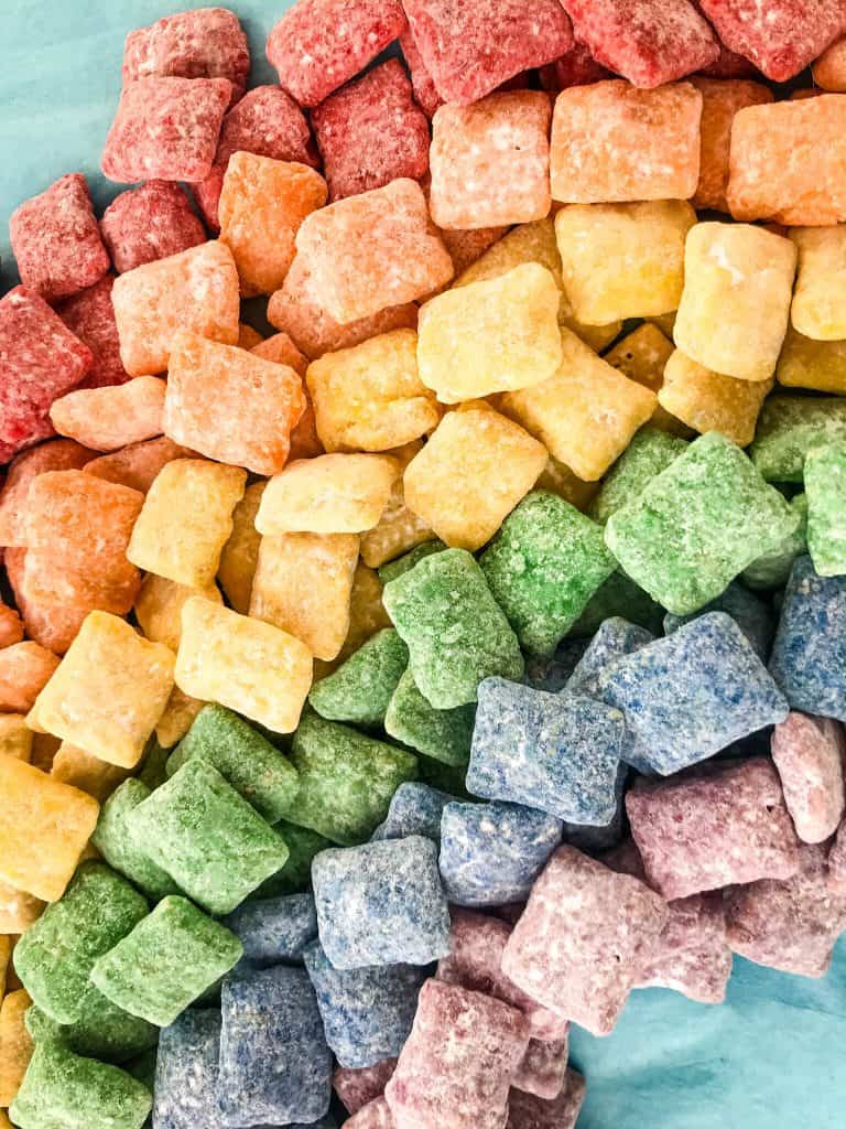 Rainbow Puppy Chow recipe is a colorful dessert perfect for a unicorn rainbow party, St Patrick's Day, or Pride month. Gluten free and vegetarian. #rainbowpuppychowrecipe #puppychow #rainbow #unicorn #pride