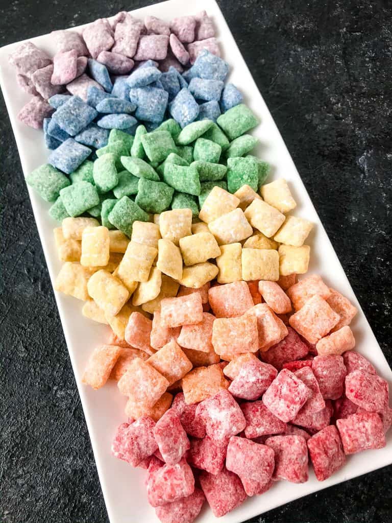 Rainbow Puppy Chow recipe is a colorful dessert perfect for a unicorn rainbow party, St Patrick's Day, or Pride month. Gluten free and vegetarian. #rainbowpuppychowrecipe #puppychow #rainbow #unicorn #pride