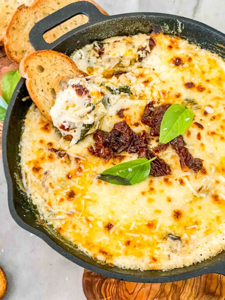 Close view of Tuscan Cheese Dip with a piece of bread in it
