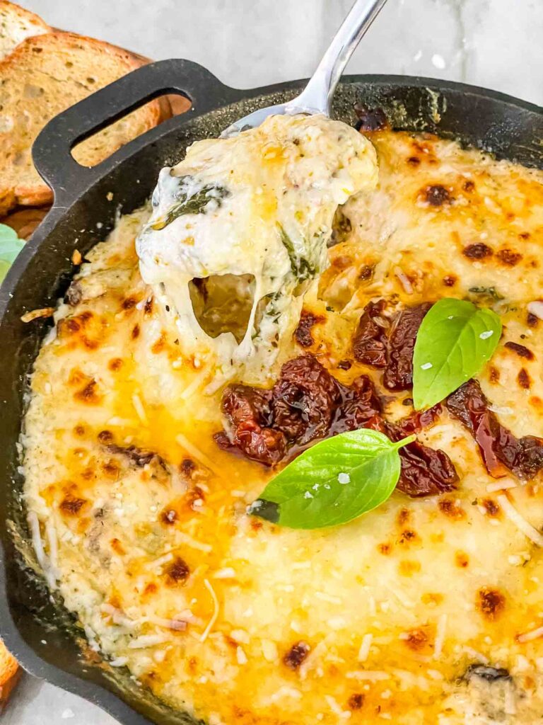 A spoon scooping some dip out of the skillet