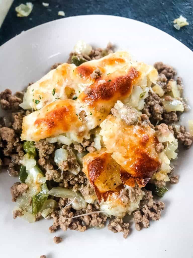 Philly Cheesesteak Tater Tot Casserole is a cheesy beef casserole recipe mixed with onion, green bell pepper, provolone cheese, and potato tater tots. An easy dinner idea for busy nights for the family. #beefcasserole #cheesesteak #hamburgercasserole