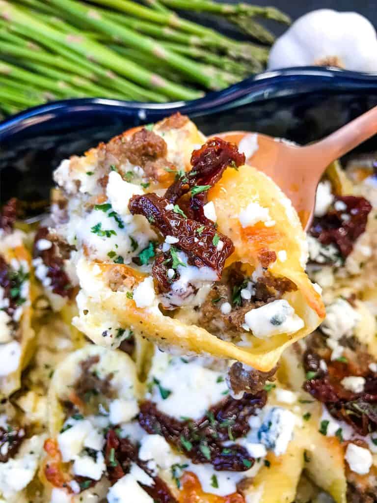 A spoon scooping Steak Gorgonzola Alfredo Stuffed Shells out of a dish