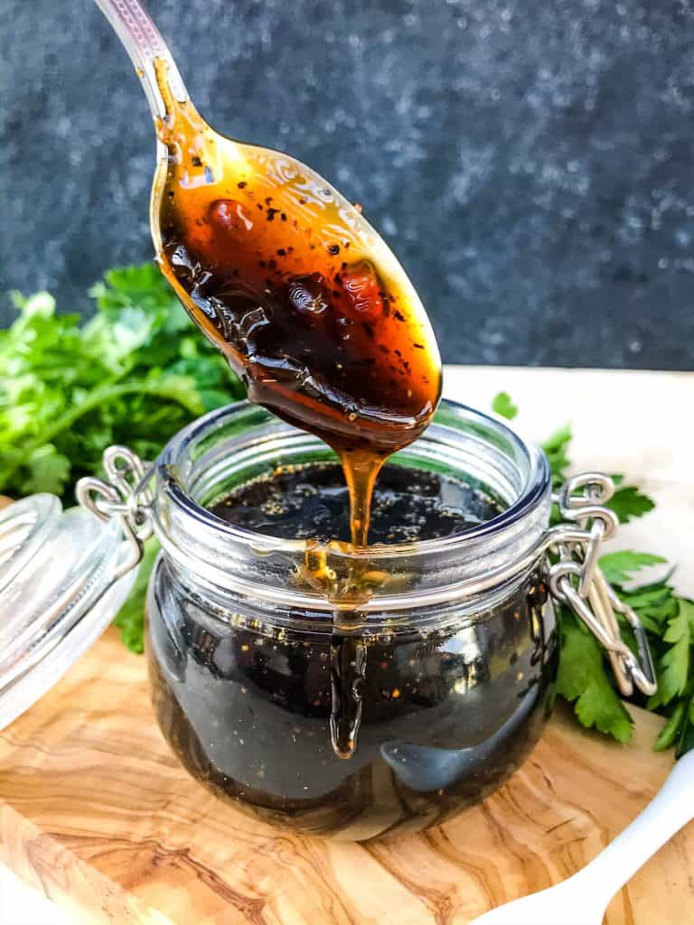 Copycat Bennigan's Guinness Glaze is a great sauce recipe inspired by the restaurant for grilling, BBQ, or St Patrick's Day. The Irish stout glaze is a thickened beer sauce that works on just about everything like chicken, steak, beef, and pork. #Guinness #Irishrecipes #StPatricksDay A spoon dripping with glaze from a small pot