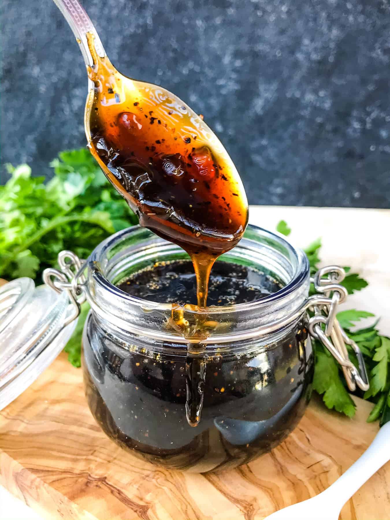 A spoon dripping Copycat Bennigan's Guinness Glaze into a glass pot