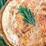 Top view of a loaf of No Knead Rustic Rosemary Bread with rosemary on it