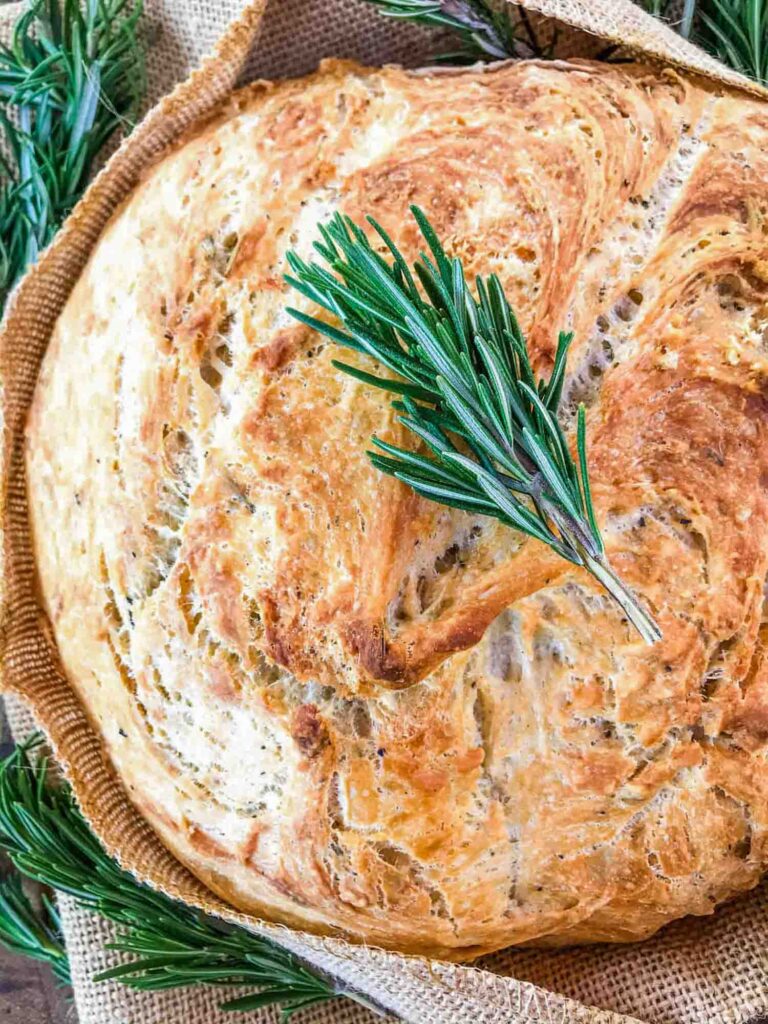 Top view of a loaf of No Knead Rustic Rosemary Bread with rosemary on it