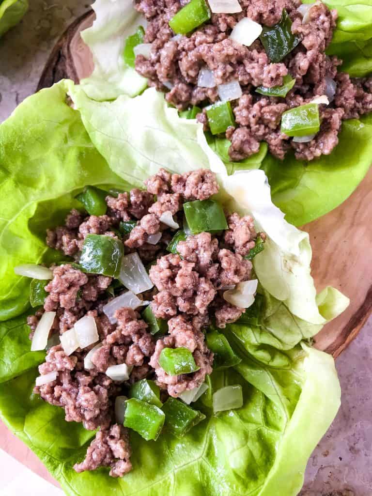 Philly Cheesesteak Lettuce Wraps are ready in less than 30 minutes! A healthy low carb, keto, gluten free recipe. Ground beef is mixed with bell pepper, onion, and provolone cheese for a simple beef lettuce cup. #phillycheesesteak #lettucewrap #groundbeef #healthyrecipe