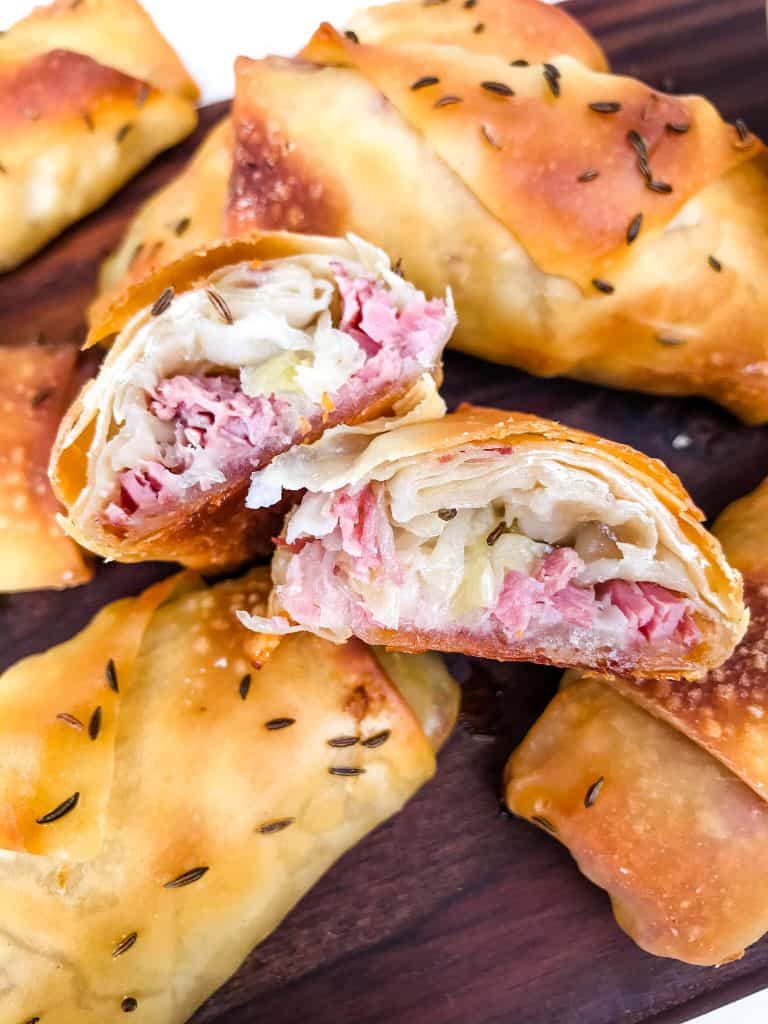 The inside of a corn beef egg roll on a pile of other egg rolls
