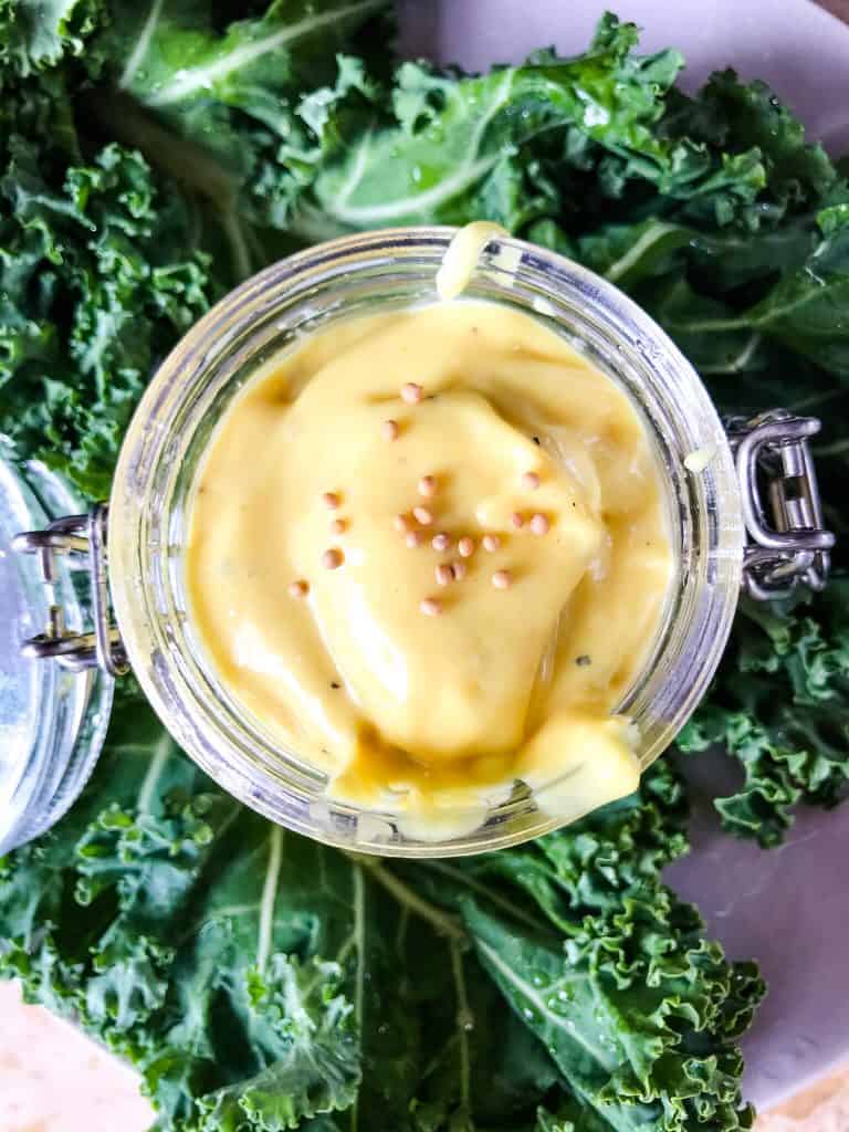 Top view of jar of Homemade Creamy Honey Mustard Sauce surrounded by kale