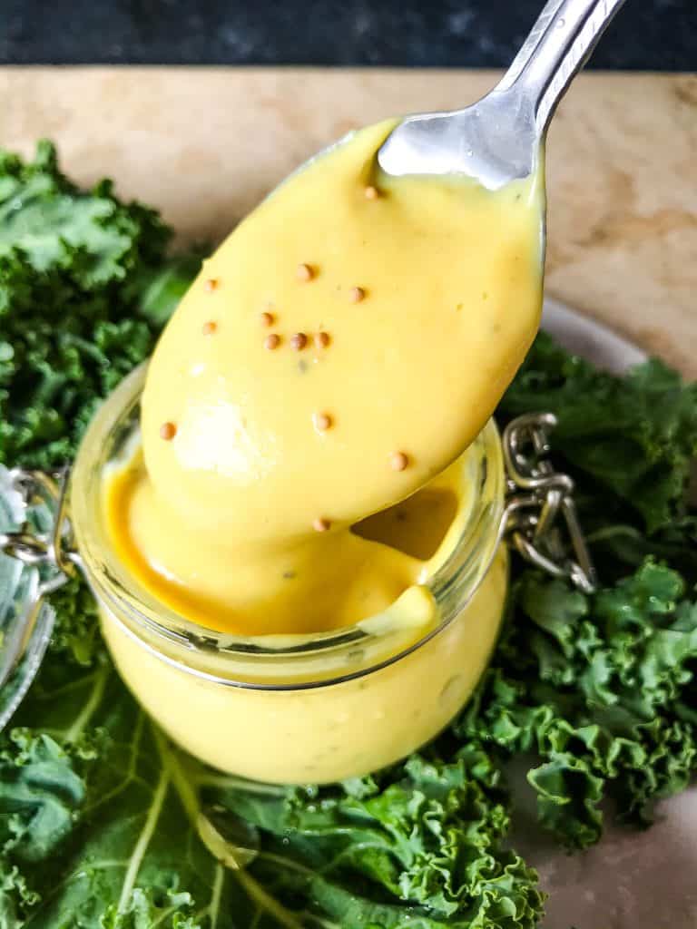 A spoon scooping Homemade Creamy Honey Mustard Sauce out of a jar