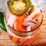 Pin of a fork pulling Escabeche (Mexican Pickled Vegetables) out of a jar with title at bottom