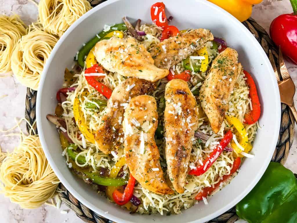 Copycat Olive Garden Chicken Scampi in a bowl surrounded by fresh pasta and peppers