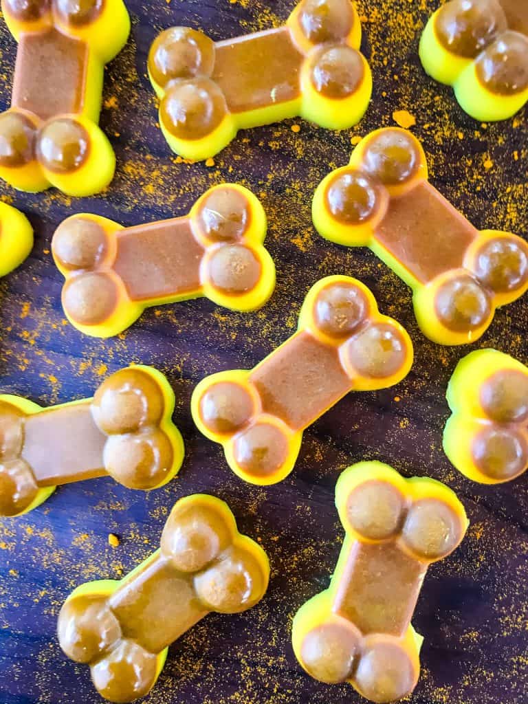 Brown and yellow Frozen Turmeric Coconut Dog Treats on a black background