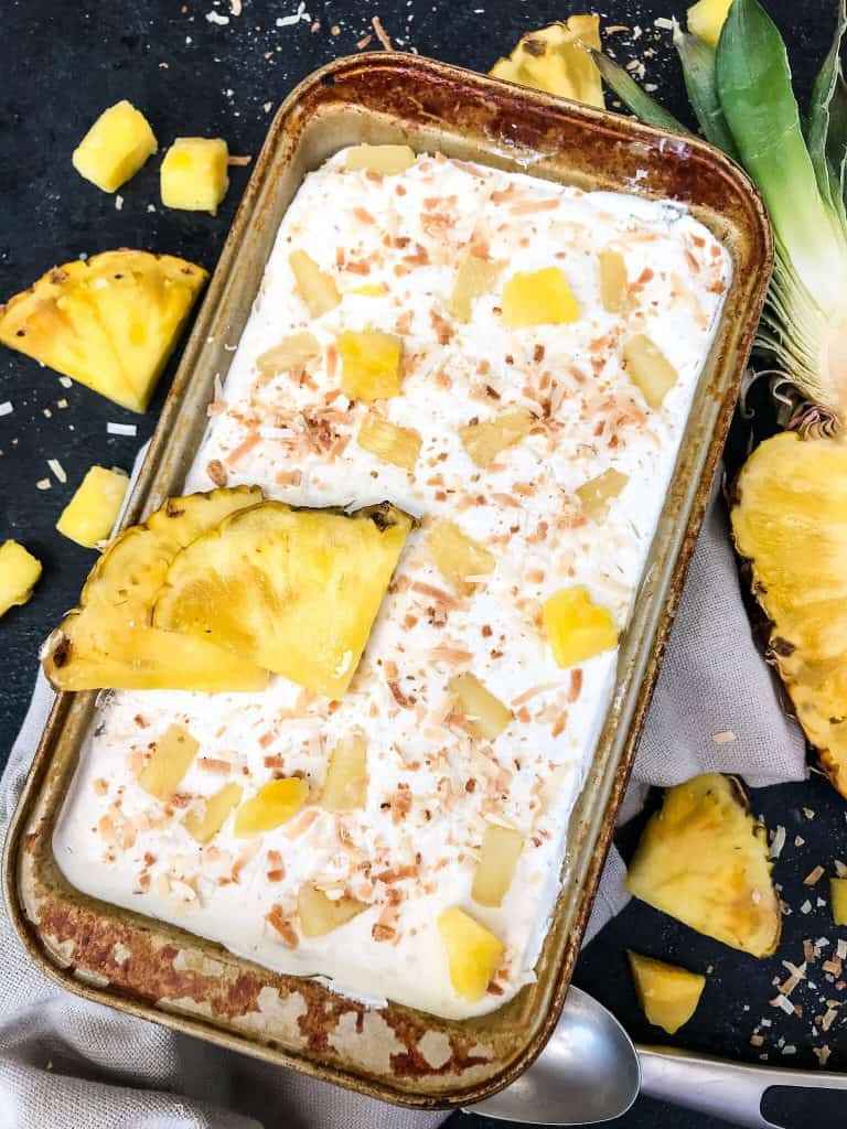 A full pan of No Churn Pina Colada Ice Cream with pineapple pieces around it