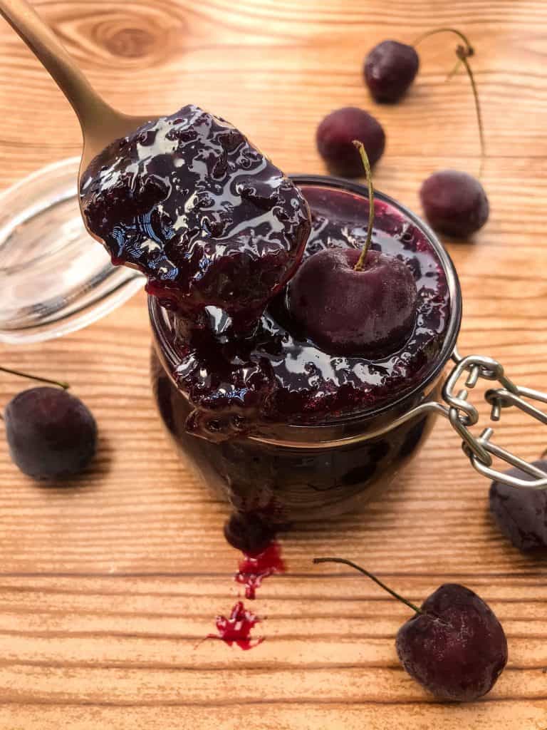 Spoon full of fruit spread coming out of a jar