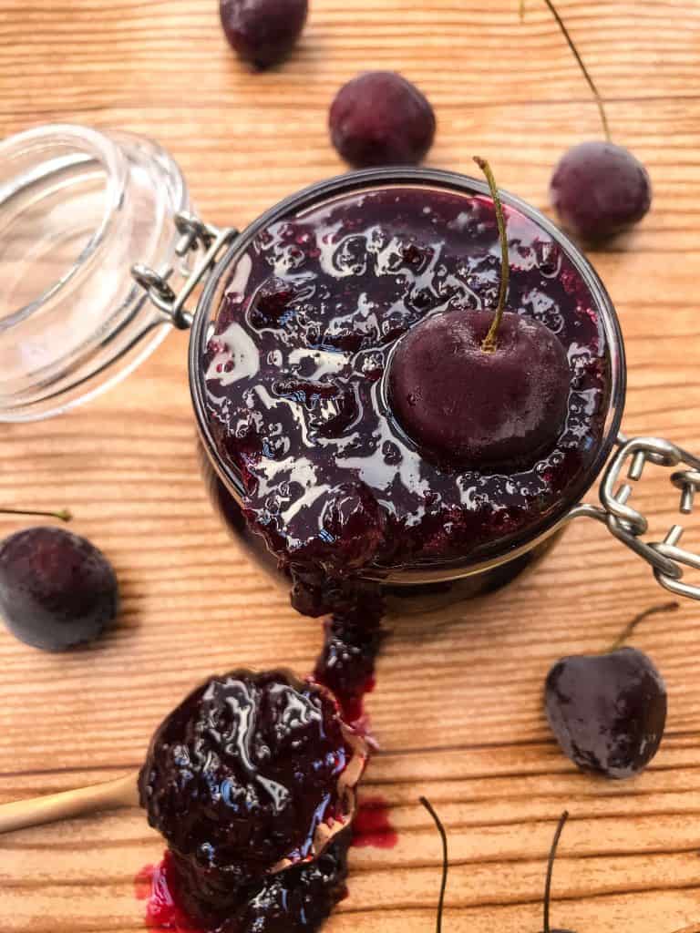Jar of jam with cherries around it