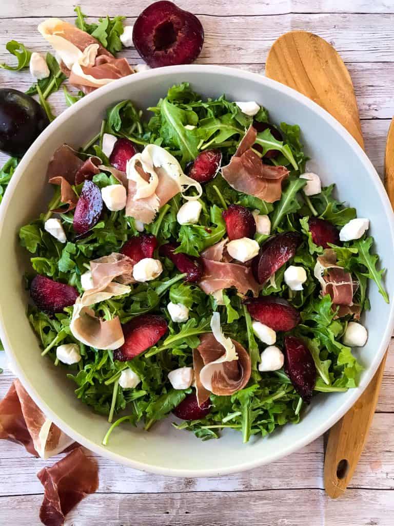 Prosciutto Plum Arugula Salad with Mozzarella in a bowl on light wood