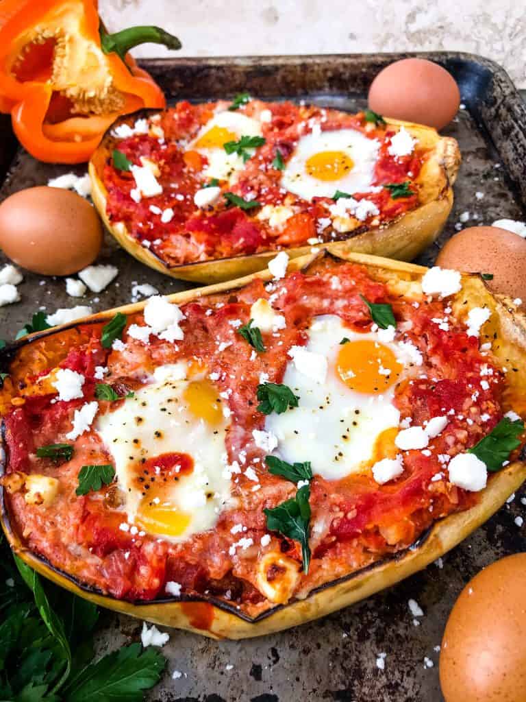 Two halves of Shakshuka Spaghetti Squash on a pan