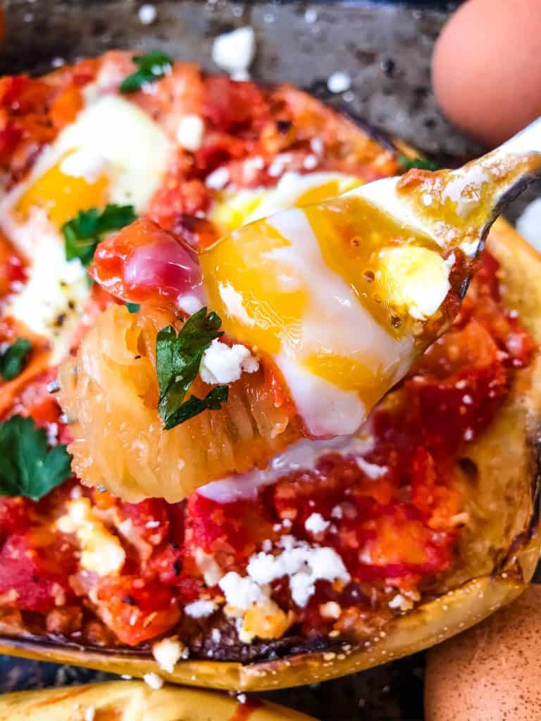 A fork pulling Shakshuka Spaghetti Squash out of the shell