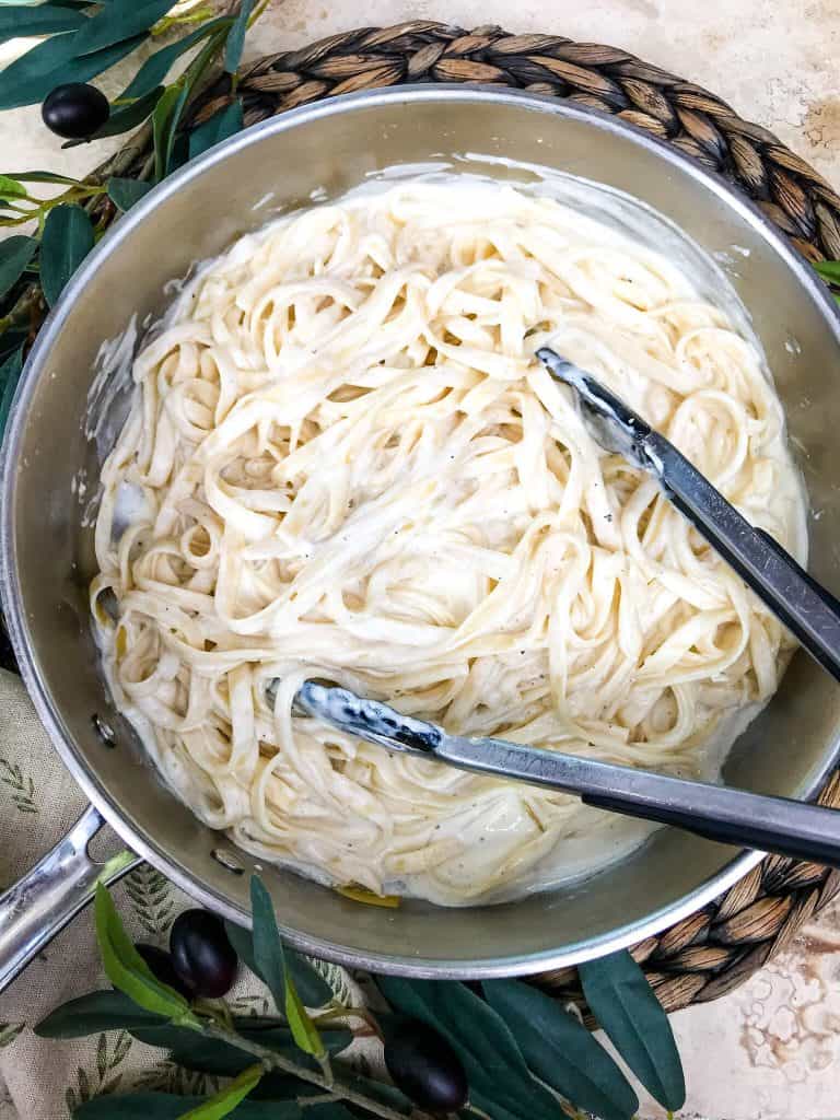 A skillet of Copycat Olive Garden Fettuccine Alfredo with tongs