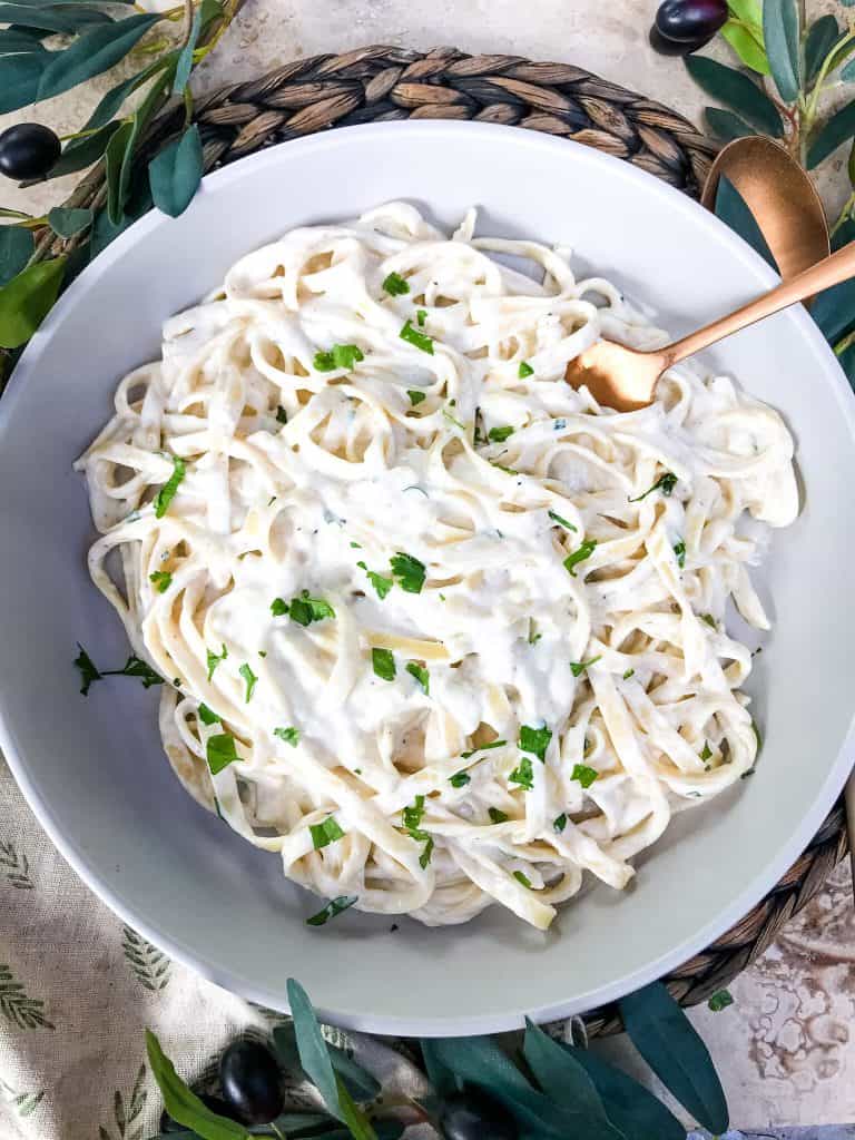 A bowl of pasta with a copper spoon