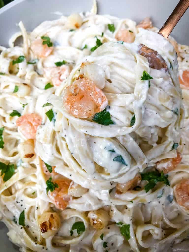 A spoon scooping Copycat Olive Garden Seafood Alfredo out of a bowl