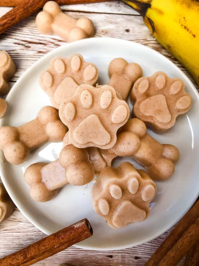 Frozen Cinnamon Banana Dog Treats on a white plate on wood surface