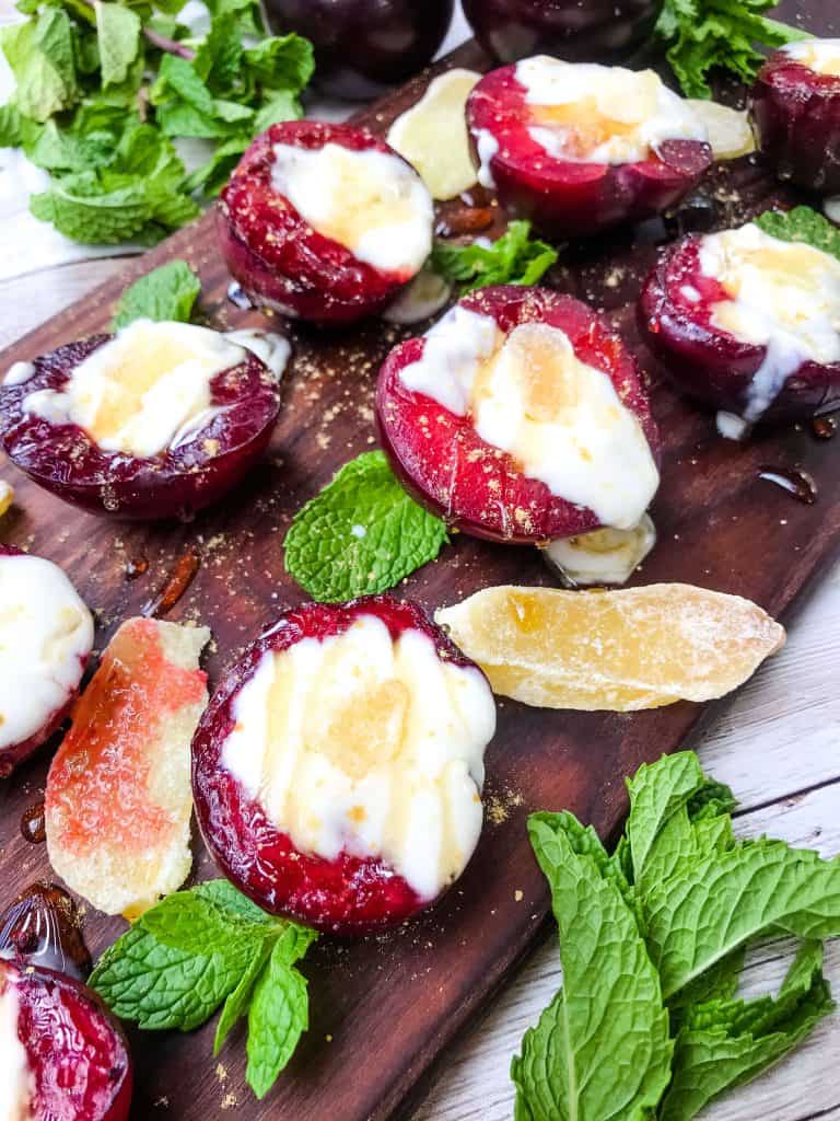 Grilled Plum Dessert with Ginger Honey Yogurt on a dark wood board with mint