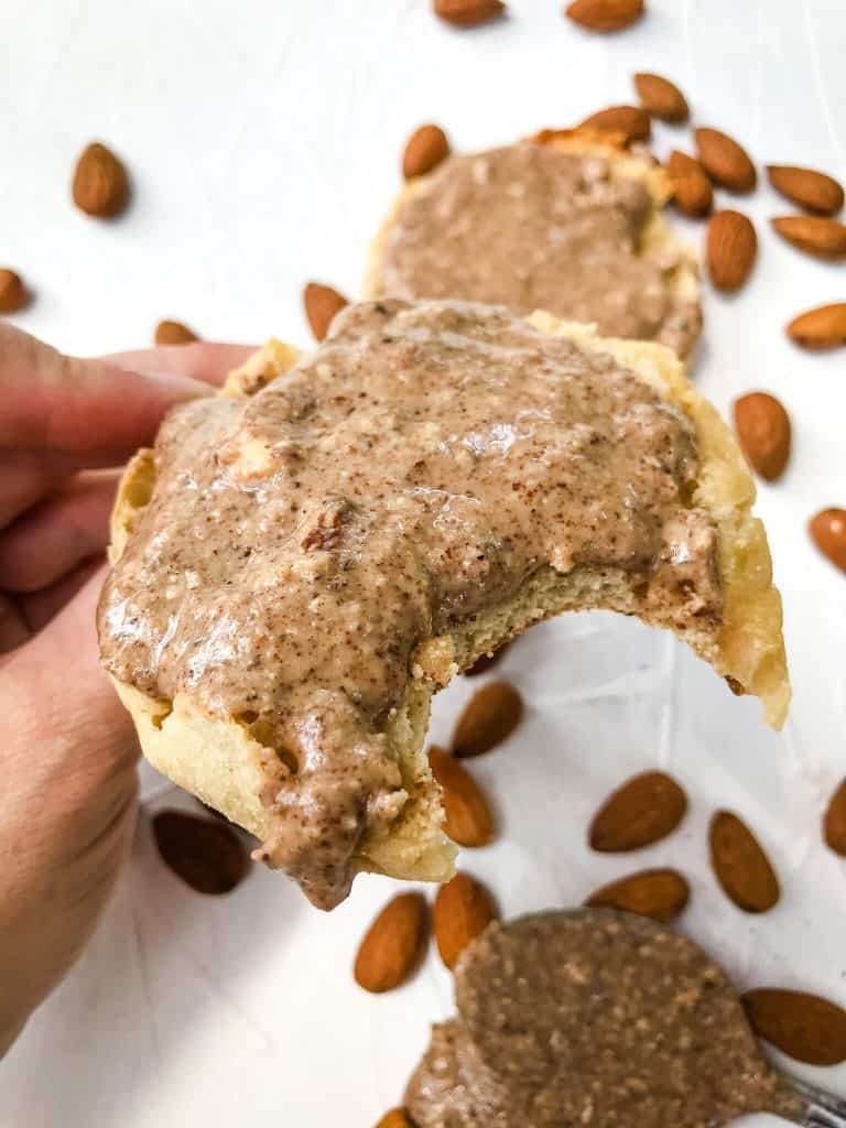 Toasted English muffin with Homemade Crunchy Almond Butter Recipe with a bite taken out of it