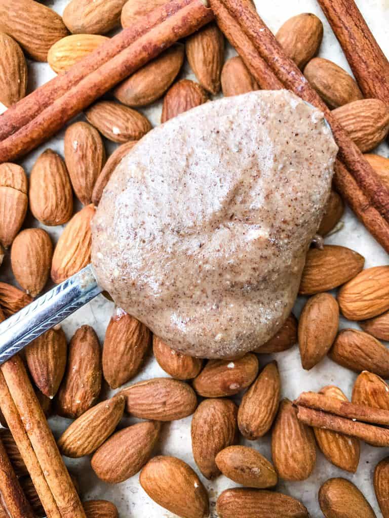 A spoon full of Homemade Cinnamon Almond Butter on top of almonds and cinnamon sticks