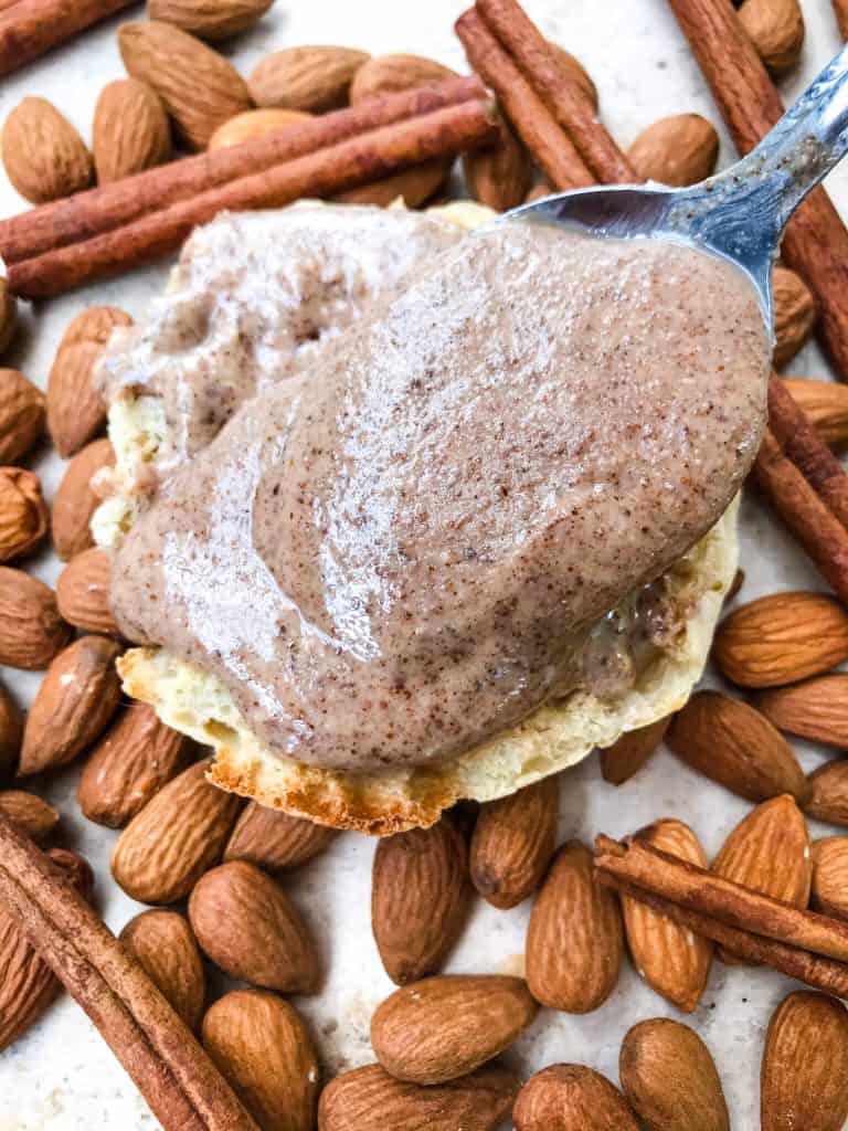 A spoon pouring nut butter on an English muffin