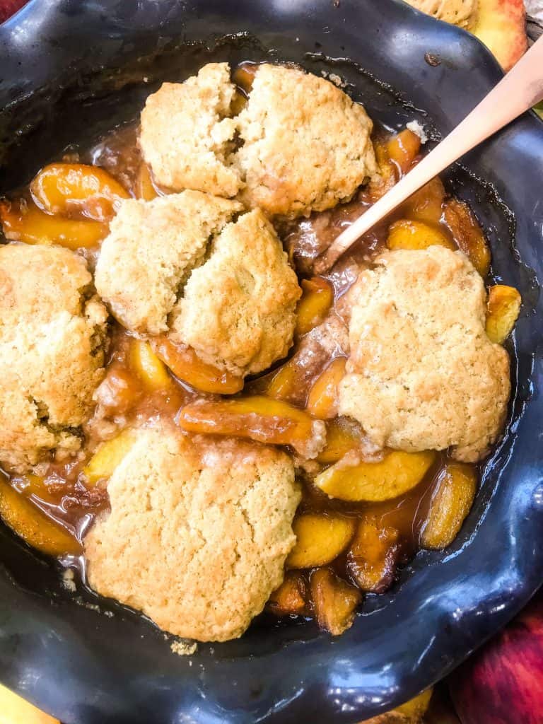 Pie dish of Easy Peach Cobbler with a spoon in it