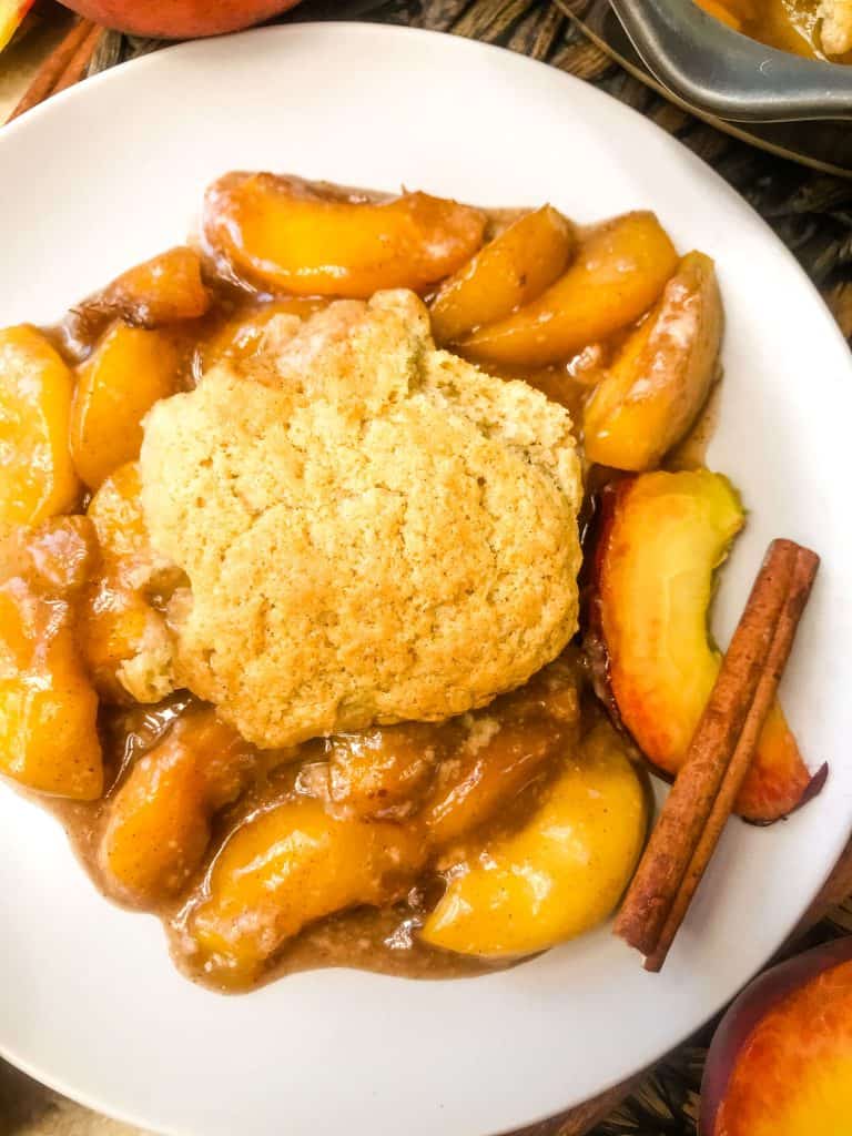 A plate of Easy Peach Cobbler with a cinnamon stick