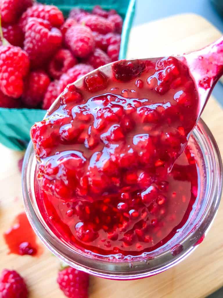 A spoon scooping Raspberry Jam Recipe out of a jar