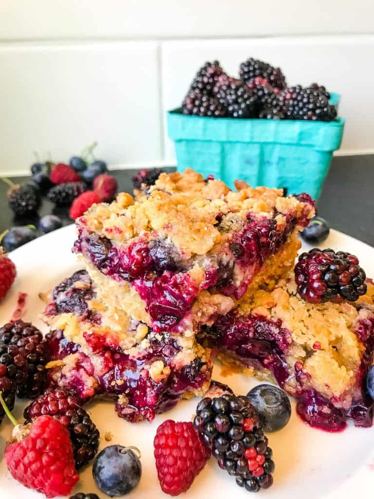 Mixed Berry Crumble Bars stacked on a plate with berries