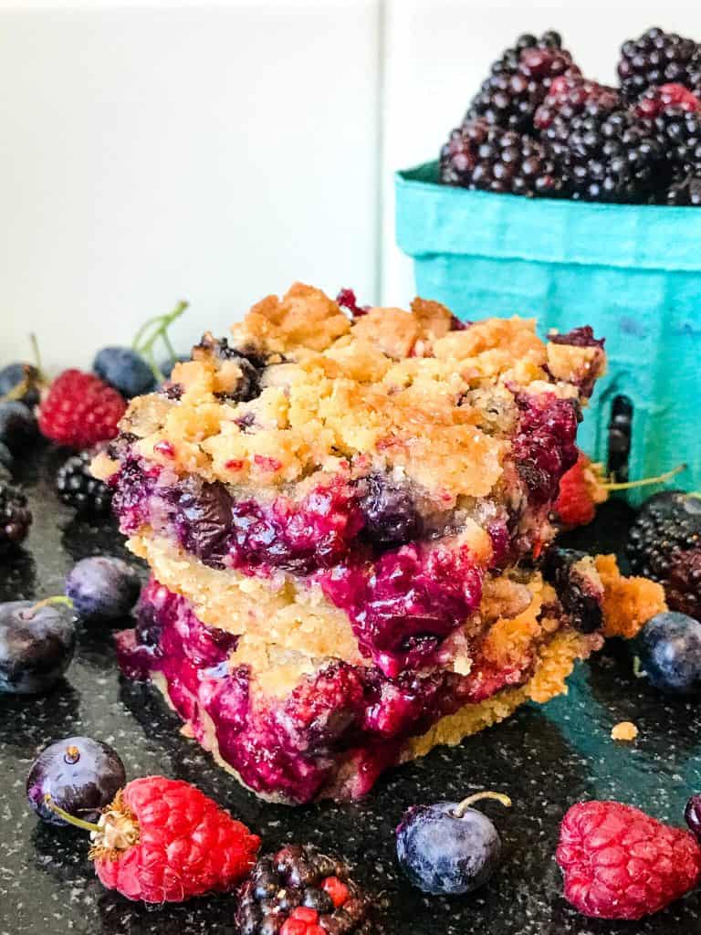 Homemade Mixed Berry Crumble Bars stacked with berries around them
