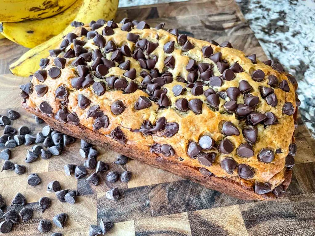 Whole Chocolate Chip Banana Bread loaf on a wood cutting board