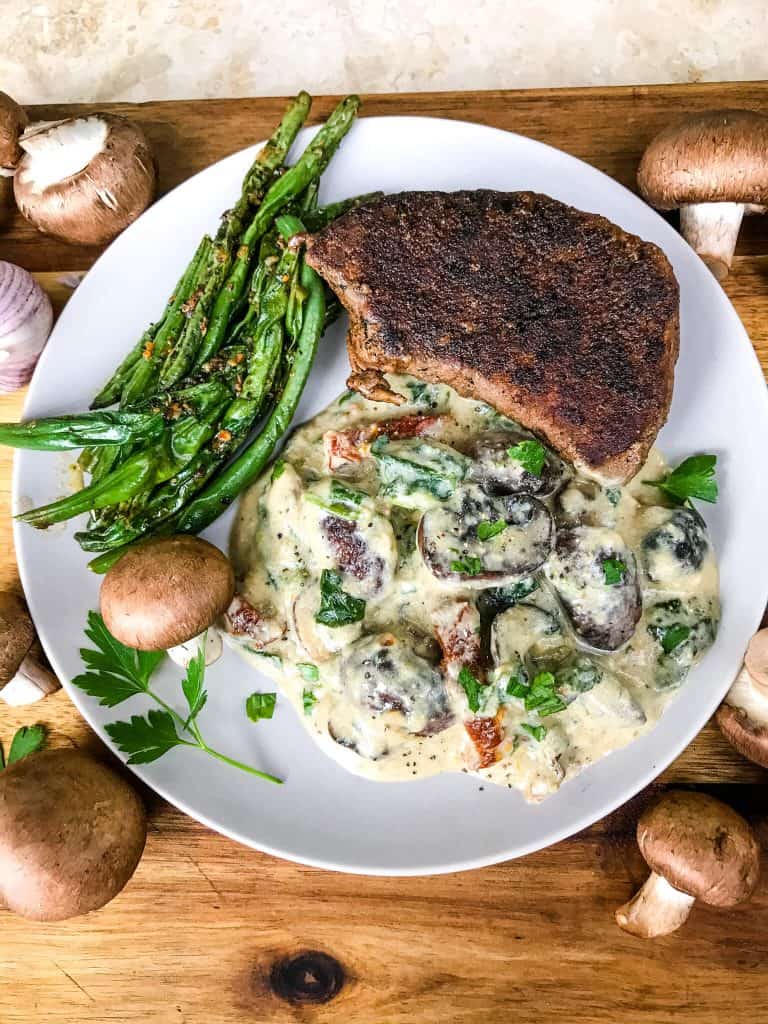 A plate with Tuscan Creamy Mushrooms, steak, and green beans