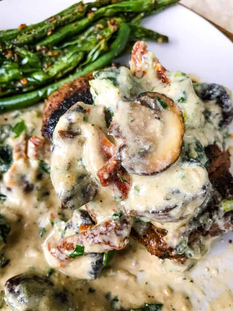 Creamy mushrooms on top of a steak