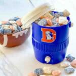 Blue, orange, and white Denver Broncos Puppy Chow in a cooler cup and on a white counter.