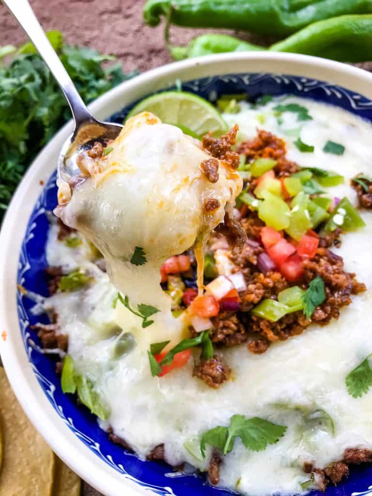 A spoon scooping Hatch Green Chile Chorizo Queso Fundido out of a dish